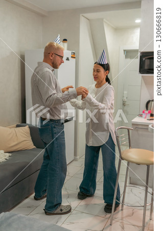 Couple Birthday Dance Apartment Celebration: Man and woman joyfully dance, celebrating a birthday in their apartment. Couple Birthday Dance Apartment Celebration: Man and woman joyfully dance, celebrating a birthday in their apartment. 130666819