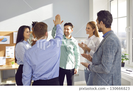 Team of happy, joyful business people celebrating success and high fiving each other 130666823