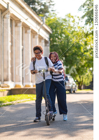 Teens enjoying a ride on a scooter and looking happy 130666846