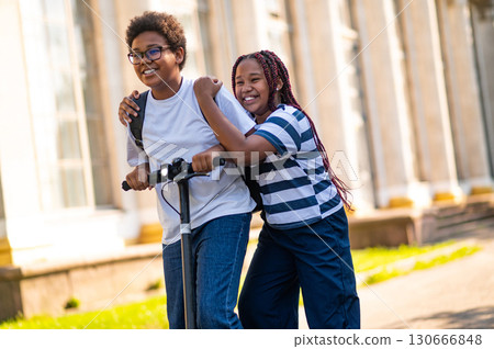 Teens enjoying a ride on a scooter and looking happy Teens enjoying a ride on a scooter and looking happy 130666848