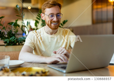 Redhead man enjoying pizza while typing on laptop Redhead man enjoying pizza while typing on laptop 130666937