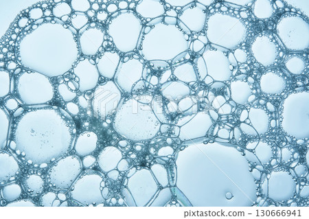The texture of soap bubbles and foam in close-up on a blue background. The texture of soap bubbles and foam in close-up on a blue background. 130666941