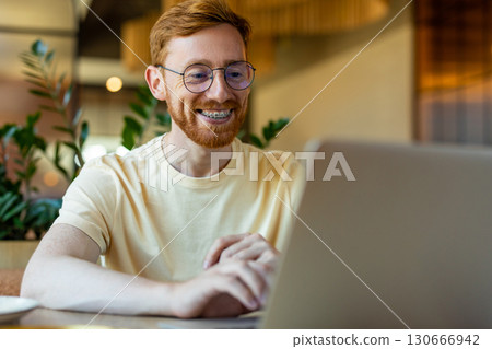 Red-haired man focused on computer during pizza lunch Red-haired man focused on computer during pizza lunch 130666942