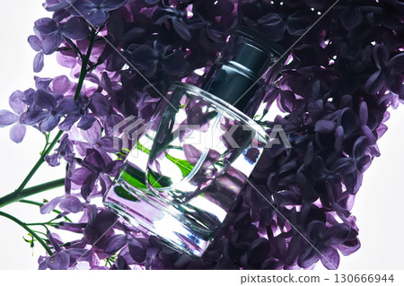 A bottle of perfume on a lilac branch in close-up. 130666944