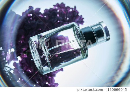 A bottle of perfume on a lilac branch in close-up. 130666945