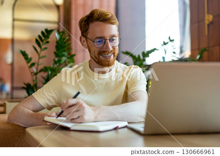 Smiling redhead with braces working on laptop with pizza Smiling redhead with braces working on laptop with pizza 130666961