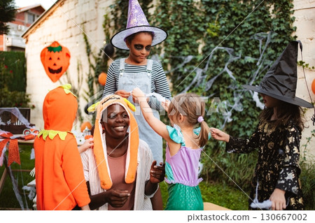 Children having fun with their babysitter at a Halloween party in the backyard Children having fun with their babysitter at a Halloween party in the backyard 130667002
