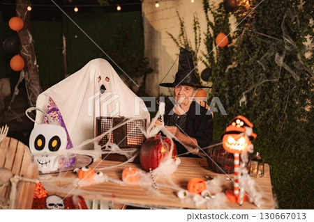 Senior woman and ghost celebrating Halloween together at home 130667013