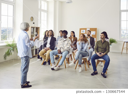 Group of business people on a meeting discussing work project sitting on chairs in office. 130667544