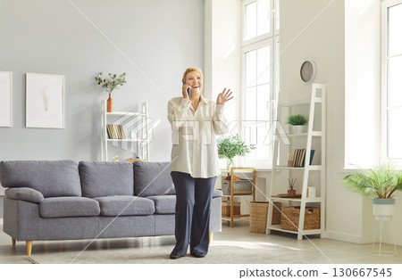 Joyful senior woman talking on smartphone, smiling, gesturing and enjoying conversation at home. 130667545