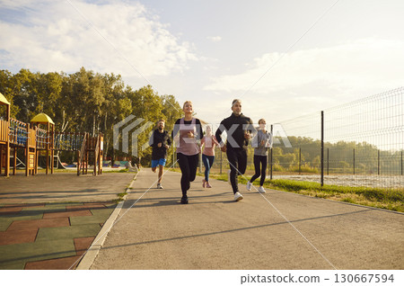 Group of sporty smiling people in sportswear jogging together in the park in nature. 130667594