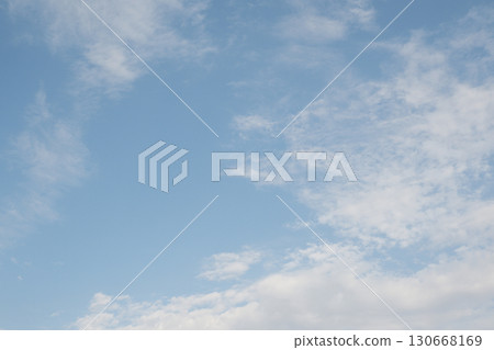 Clear sky with scattered white clouds. The clouds vary in size and shape, creating a serene atmosphere. Background light blue. Clear sky with scattered white clouds. The clouds vary in size and shape, creating a serene atmosphere. Background light blue. 130668169