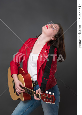 Female guitarist adopts posture with head thrown back, and she performs soulful rendition on guitar. Woman's exuberant performance of guitar, passion, contributes to performance's overall dynamism Female guitarist adopts posture with head thrown back, and she performs soulful rendition on guitar. Woman's exuberant performance of guitar, passion, contributes to performance's overall dynamism 130668312