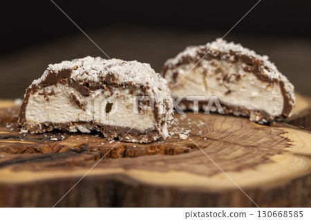 halved marshmallows in chocolate sprinkled with coconut chips, sweet dessert marshmallows in milk chocolate with coconut cut in half 130668585