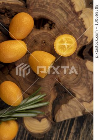 fresh sweet kumquat cut into halves on a table, sliced orange kumquat fruits lie on the table during cooking 130668588