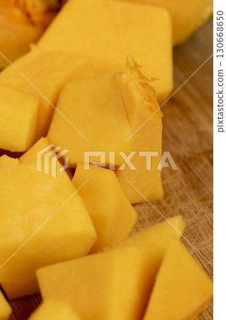 cut bright orange ripe pumpkin for cooking, cut into pieces sweet pumpkin in the kitchen, closeup 130668650