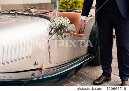 Groom in a vintage convertible retro car at a wedding. 130668746