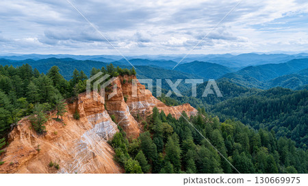 Colorful rock formations tower over dense forests in a mountainous landscape showcasing nature's beauty in the twilight hours of the day 130669975