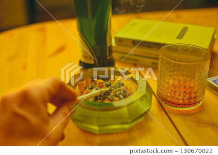 A hand holding a smoking cigarette. A hand holding a smoking cigarette. The concept of alcoholism, tobaccoism, and addiction. 130670022