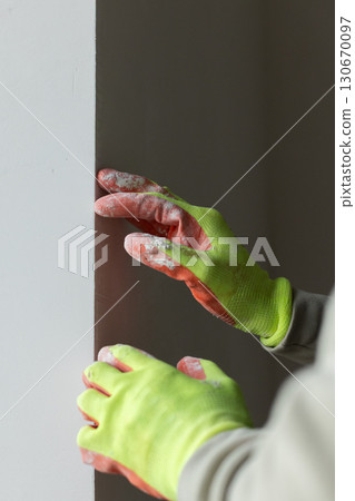 Worker checking a window slope. Preparation of window slopes before painting. 130670097