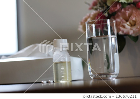 Tissue paper, a cup of water, a syrup container, an image of taking medicine, flowers 130670211
