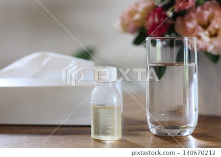 紙巾、一杯水、一個糖漿容器、一張服藥的圖片、鮮花 130670212