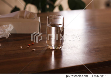 捲起的薄紙和一杯水、藥丸、白色紙巾盒，室內 130670358