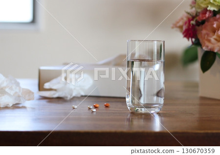 捲起的薄紙和一杯水、藥丸、白色紙巾盒，室內 130670359