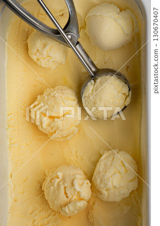 Vanilla ice cream scoops in tray with scoop utensil, close-up food background Vanilla ice cream scoops in tray with scoop utensil, close-up food background 130670407