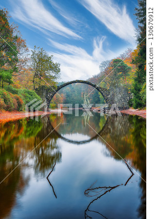 Amazing autumn landscape in Kromlau Rhododendron Park . Rakotz Bridge (Rakotzbrucke, Devil's Bridge) 130670912