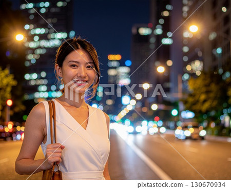 A woman wearing a white dress walking through the city at night 130670934