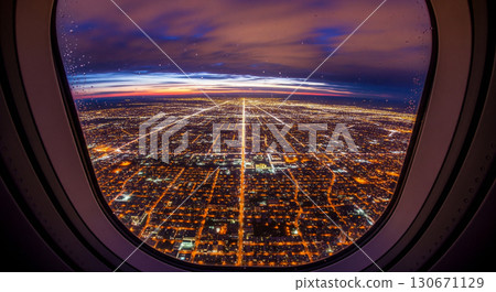 As the airplane descends, a stunning fisheye perspective reveals a vibrant city skyline illuminated with thousands of lights against the dark night sky, showcasing the urban landscape's vastness. 130671129