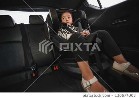toddler girl sitting in car seat, safety baby chair travelling 130674303