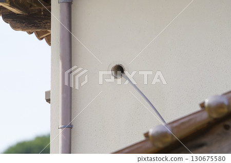 Air conditioning piping attached to the exterior wall of a house 130675580