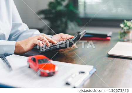 Dealership service desk, professional car salesman assists client with sale, finance documents for vehicle, ensuring smooth business transaction in retail transportation sector through signed contract 130675723