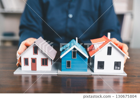 House model placed on table alongside coins, paperwork symbolizes real estate investment, property valuation, representing financial planning, mortgage options, market analysis in property business. 130675804