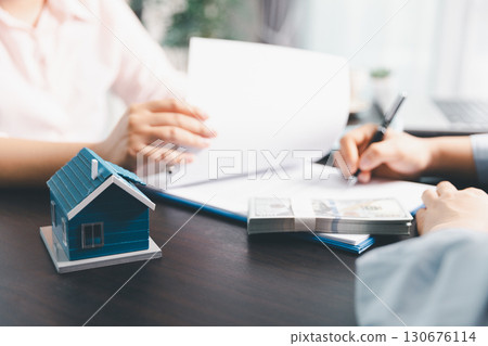 Woman real estate sale agent, client after signing agreement contract real estate with approved mortgage application form concerning mortgage loan offer, house insurance. contract agreement in office 130676114