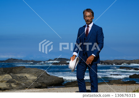 Portrait of a dandy middle-aged man in a suit at the sea 130676315