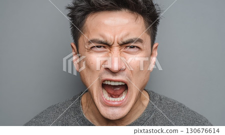 Angry asian man shouting with open mouth on gray background 130676614