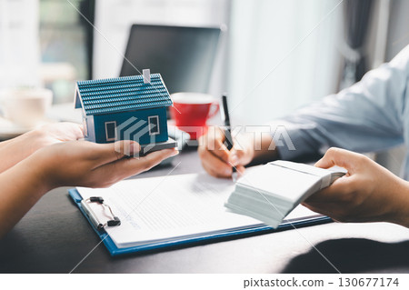 Woman real estate sale agent, client after signing agreement contract real estate with approved mortgage application form concerning mortgage loan offer, house insurance. contract agreement in office 130677174