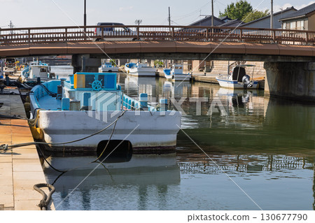河邊排列著房屋，停泊著漁船，還有一座橋 130677790