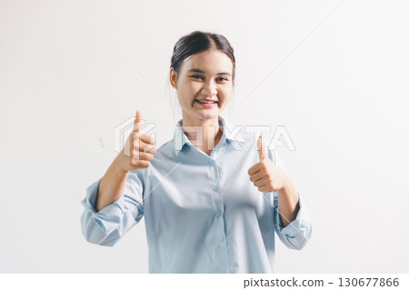 Asian woman rejoicing, looking happy, champion, fist pump gesture, standing over white background. young woman had happy, positive expression on her face, highlighted by bright smile. 130677866