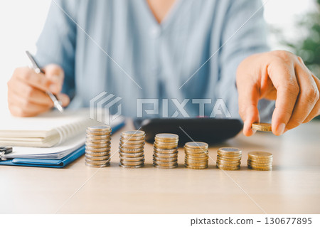 Hand places coin into saving jar, representing how smart finance, investment, banking practices turn money, cash, currency into financial wealth drives business growth and strengthens the economy. Hand places coin into saving jar, representing how smart finance, investment, banking practices turn money, cash, currency into financial wealth drives business growth and strengthens the economy. 130677895