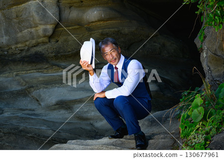 A man in a suit standing in a sea cave. A business image symbolizing challenge and determination. 130677961
