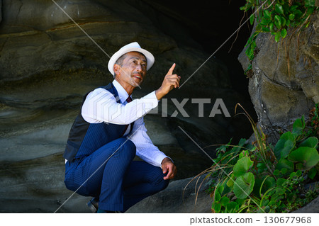 A man in a suit standing in a sea cave. A business image symbolizing challenge and determination. 130677968