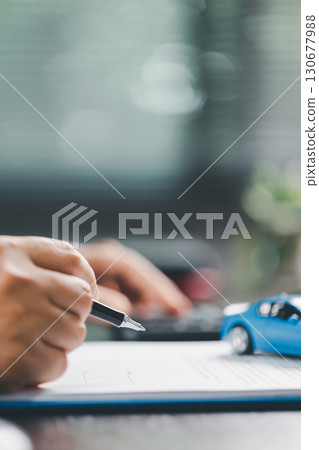 Client is signing the contract and insurance document for the purchase of a vehicle, finalizing finance and loan agreements that mark the approval of a smart investment and successful car deal. 130677988