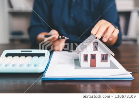 House model placed on table alongside coins, paperwork symbolizes real estate investment, property valuation, representing financial planning, mortgage options, market analysis in property business. House model placed on table alongside coins, paperwork symbolizes real estate investment, property valuation, representing financial planning, mortgage options, market analysis in property business. 130678109