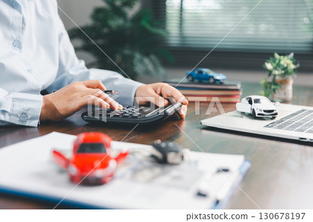 Dealership service desk, professional car salesman assists client with sale, finance documents for vehicle, ensuring smooth business transaction in retail transportation sector through signed contract 130678197
