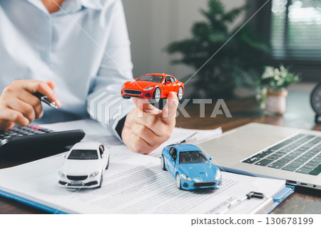 Businesswoman signing car insurance document or lease paper. Writing signature on contract or agreement. Buying or selling new or used vehicle. Car keys on table. Warranty or guarantee. Businesswoman signing car insurance document or lease paper. Writing signature on contract or agreement. Buying or selling new or used vehicle. Car keys on table. Warranty or guarantee. 130678199