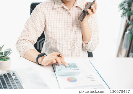 Accountant working on desk using calculator for calculate finance report in office. business finance, calculate tax by organizing financial documents, tracking income investment, accounting by hand. 130678457